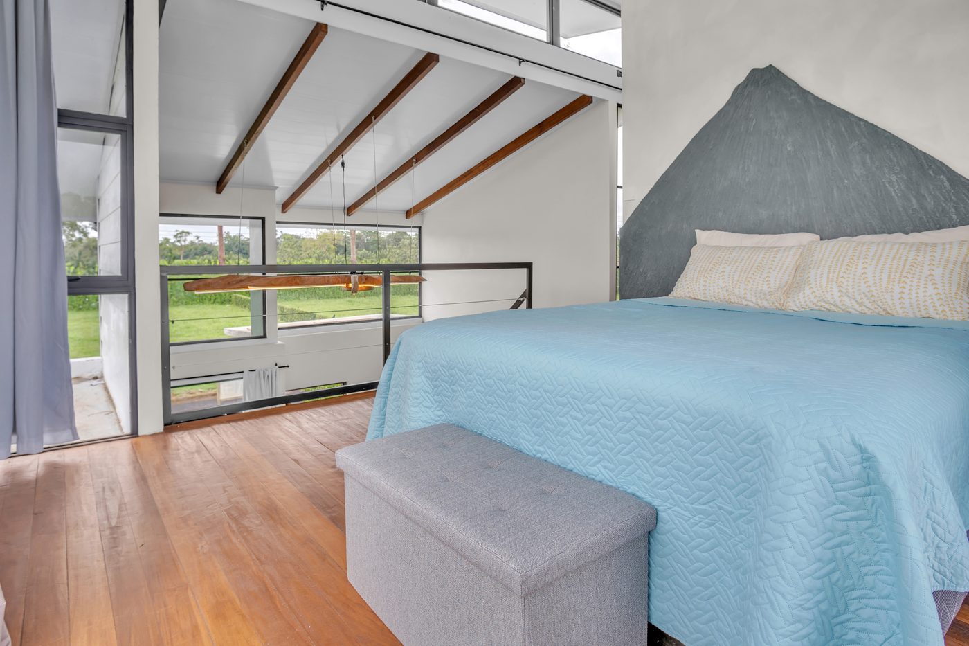 Habitación con piso de madera, cielo alto y ventanales