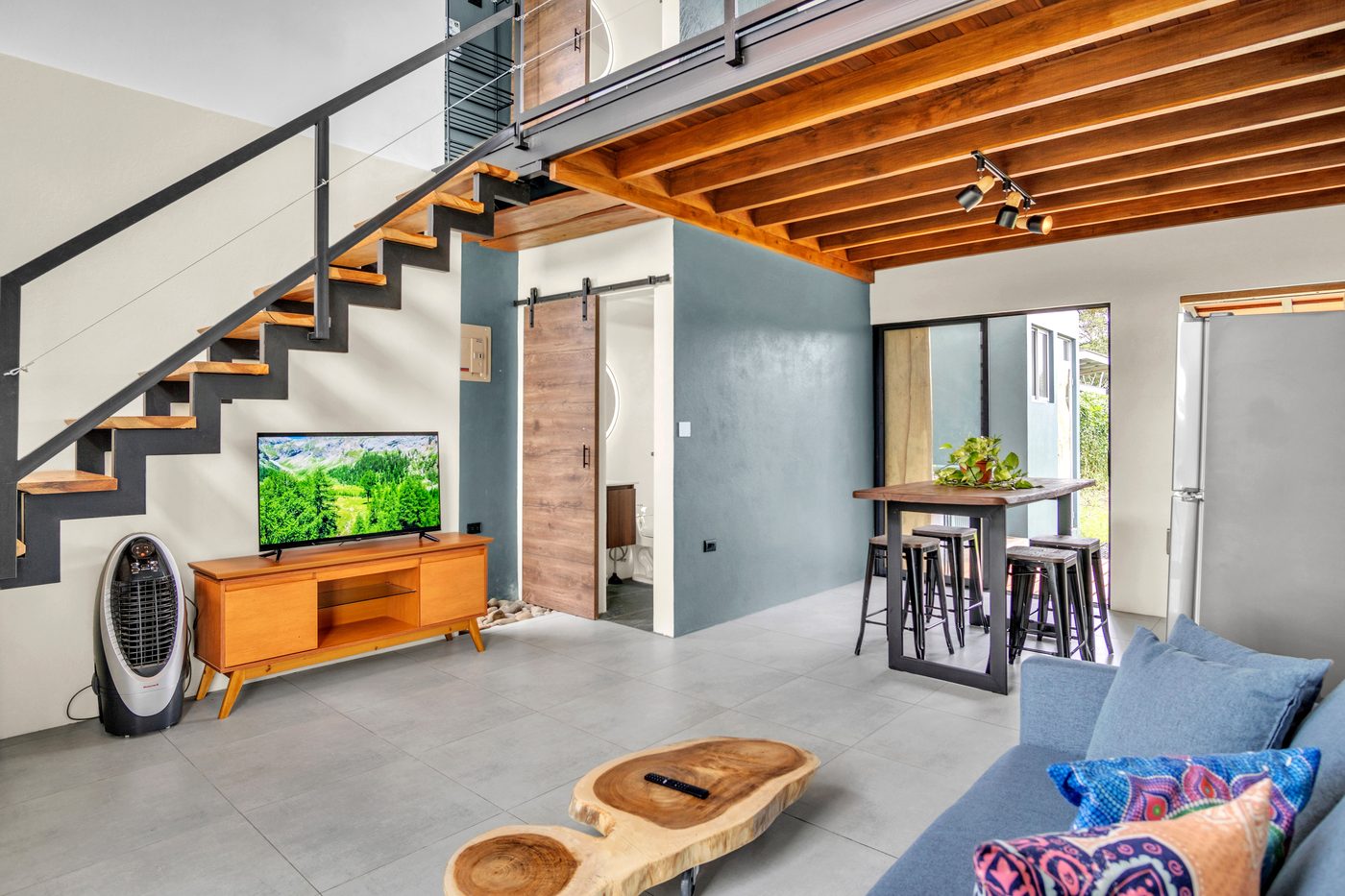 Sala de Casa La Fortuna con escalera flotante de madera y acero