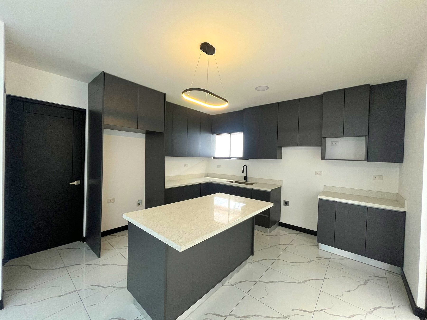 Cocina con muebles grises de melamina, sobres de cuarzo e isla central
