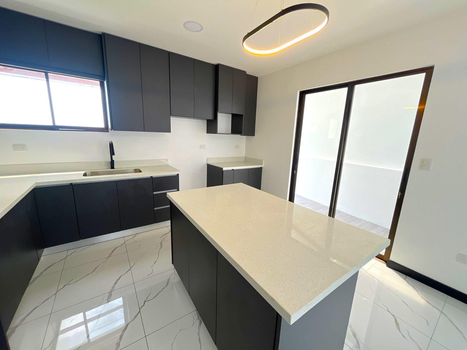 Cocina con isla y puerta corrediza de vidrio hacia el patio
