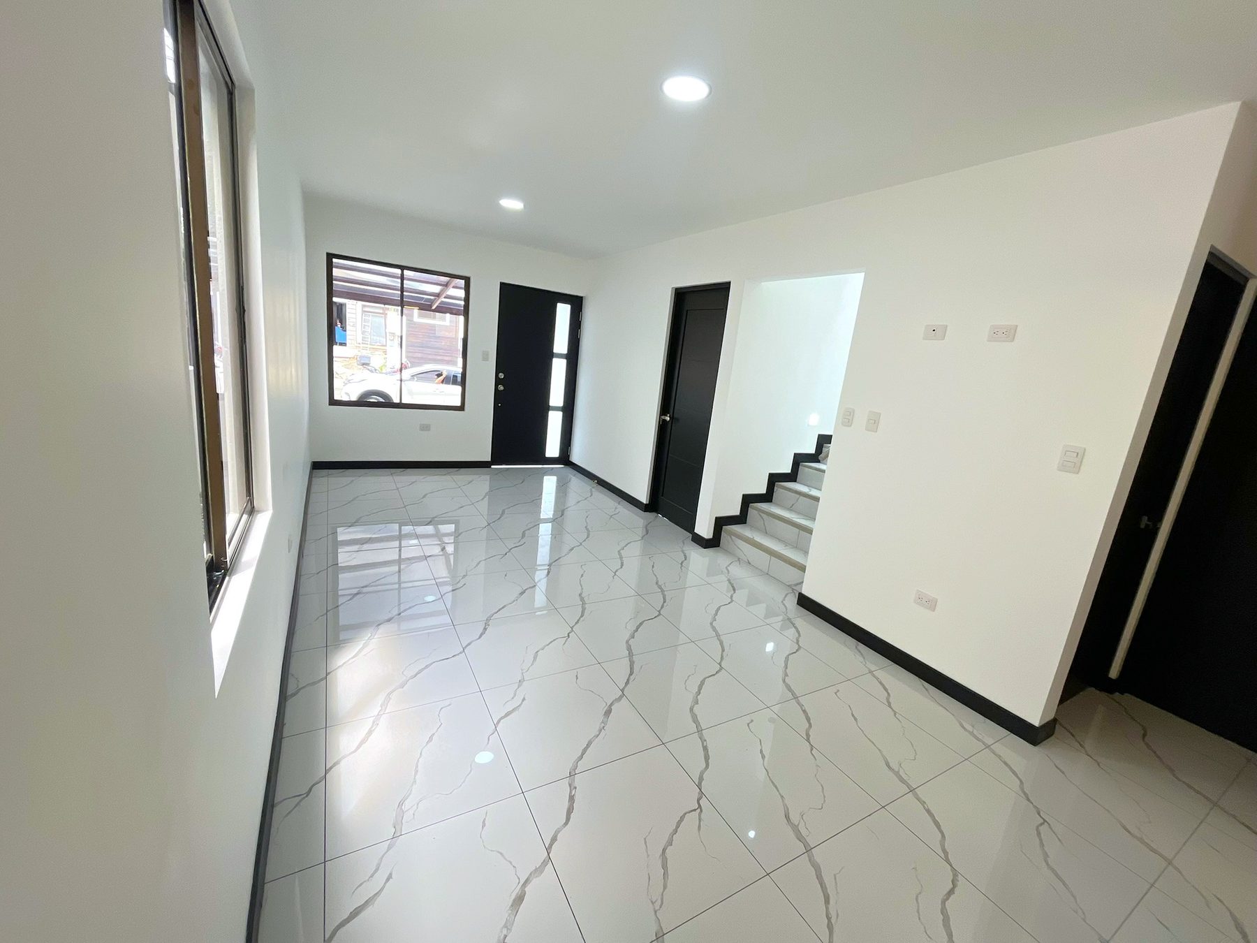 Sala de la planta baja vista desde la cocina, con la puerta principal al fondo