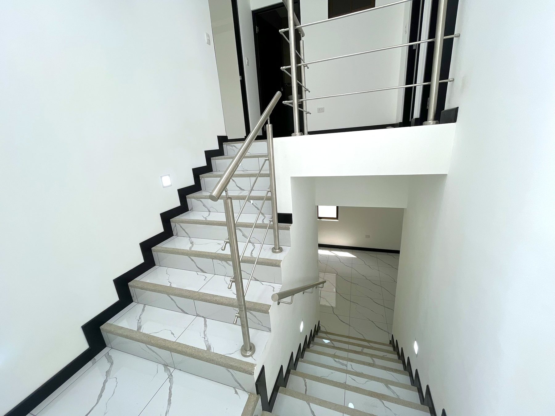 Escalera enchapada con pasamanos metálico y luces de paso