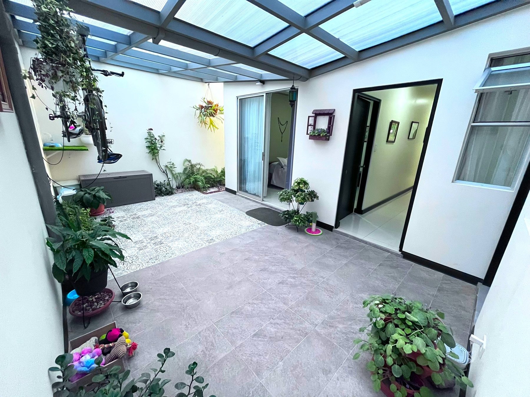 Patio techado con piso enchapado, jardín interno y acceso a la habitación principal