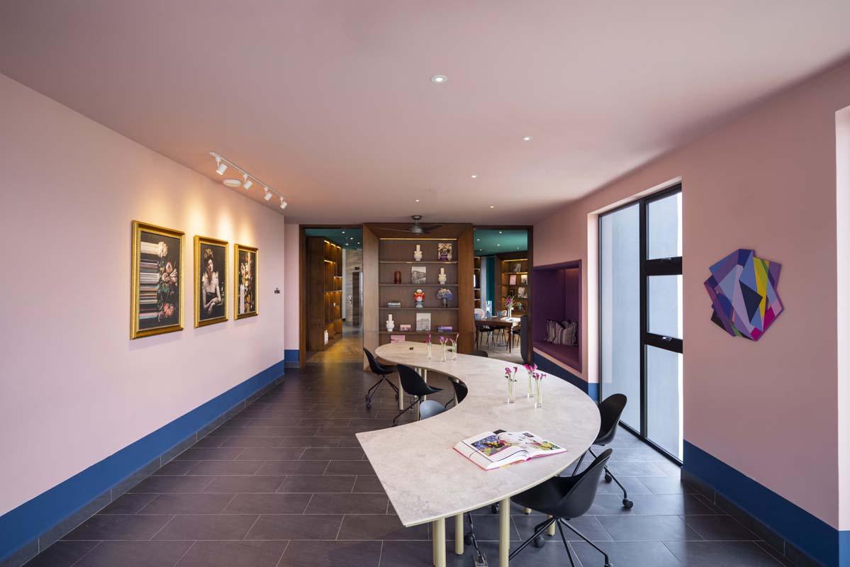 Área de coworking con mesa curva y biblioteca