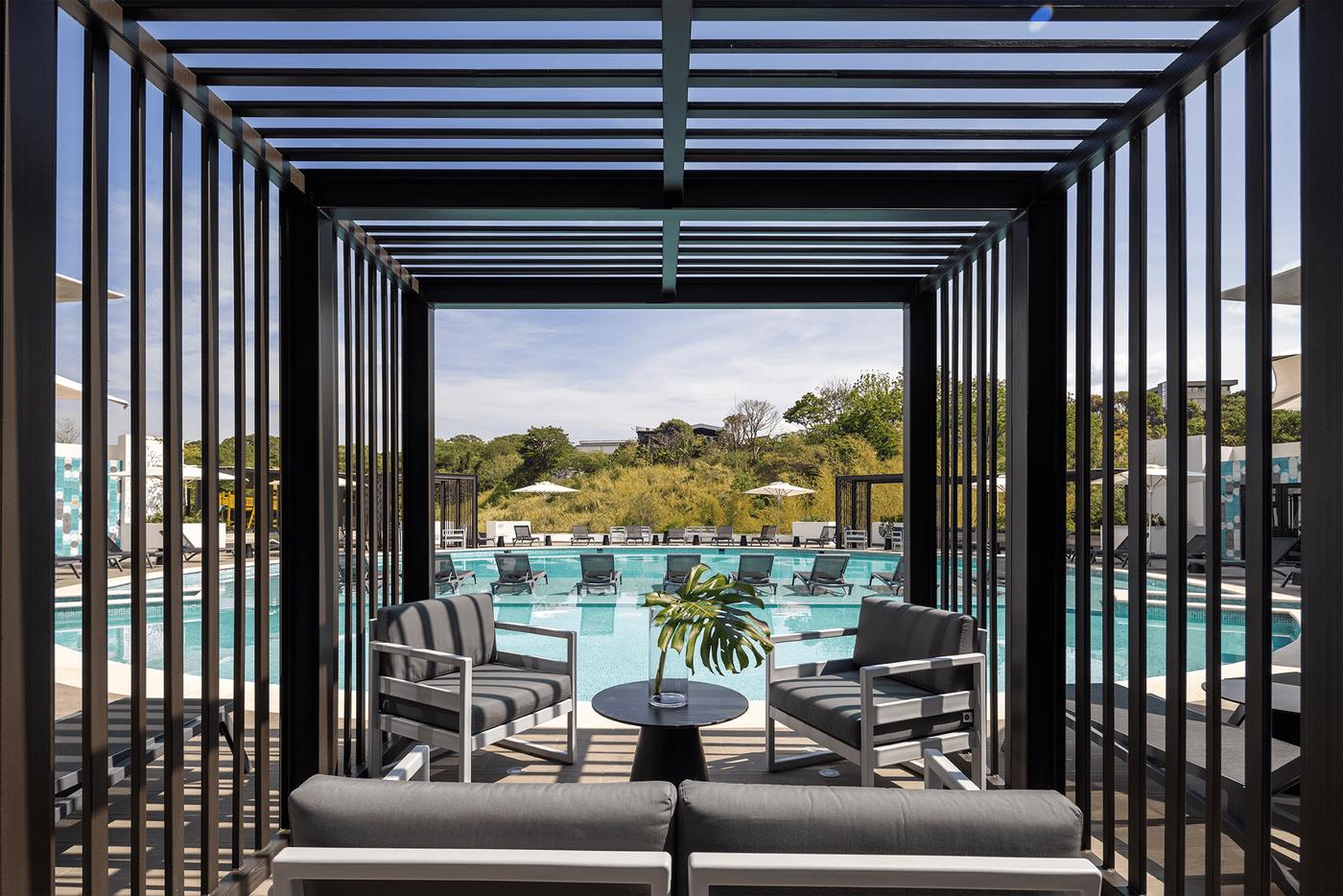 Pérgola con sala exterior frente a la piscina