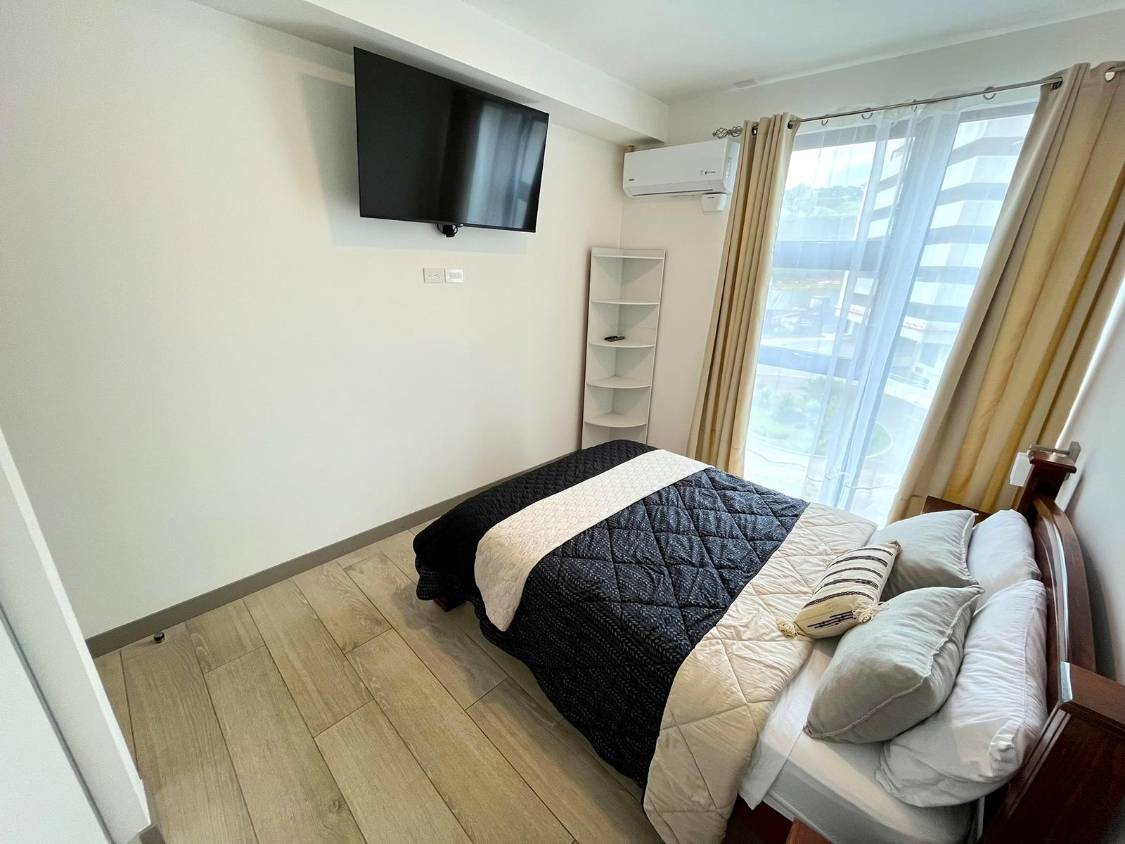 Habitación con cama, televisor en la pared y aire acondicionado