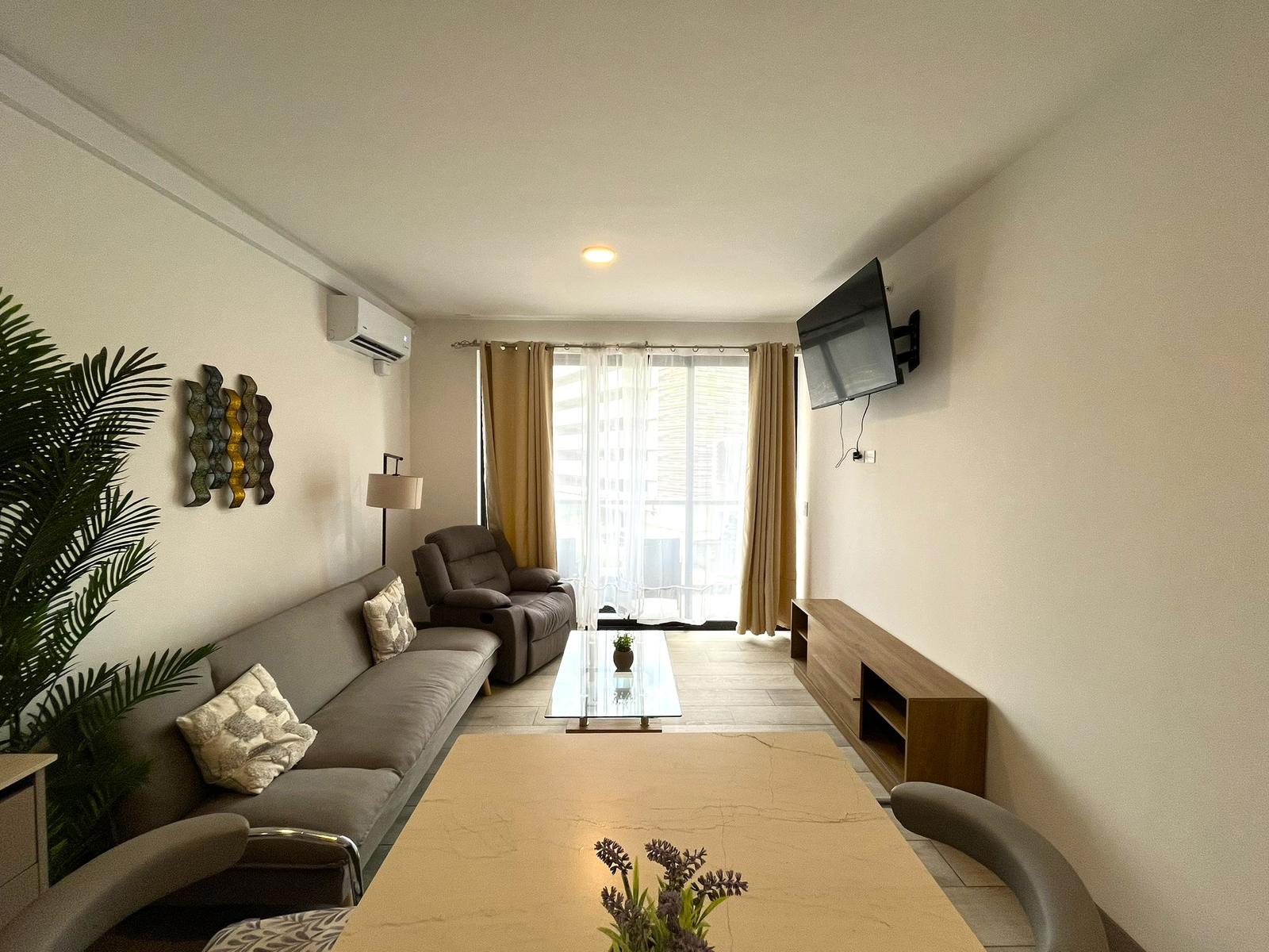 Sala con sofá, sillón reclinable, televisor y salida al balcón