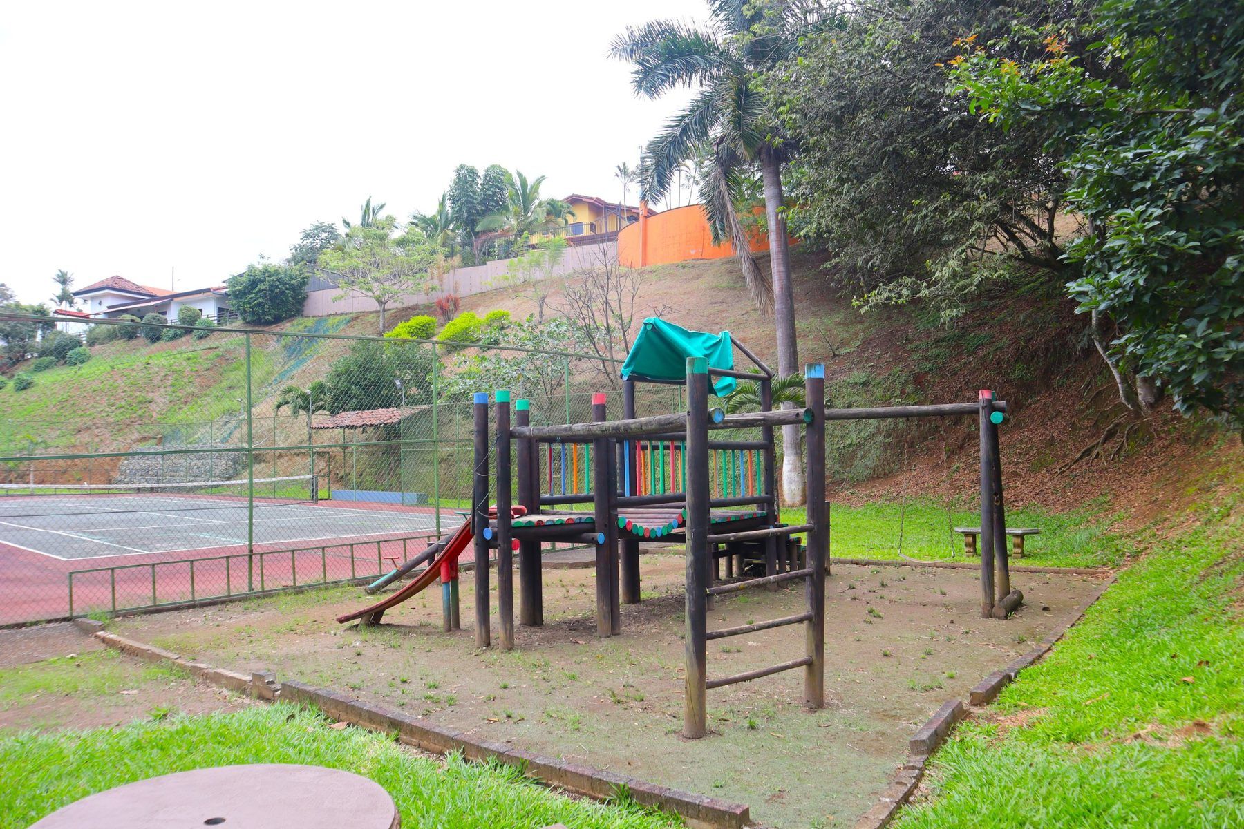 Juegos infantiles de madera junto a la cancha de tenis del condominio