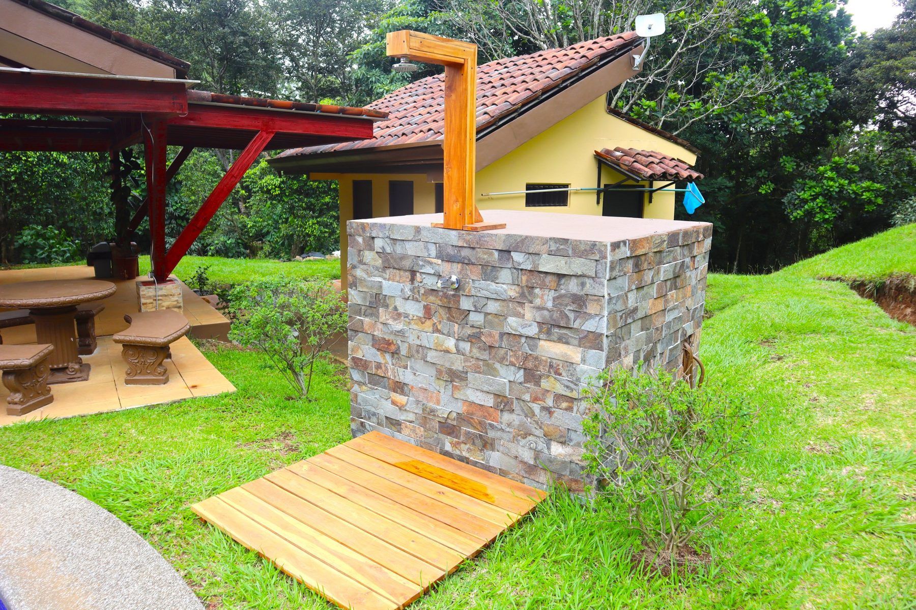 Ducha exterior de piedra a la salida de la piscina del condominio