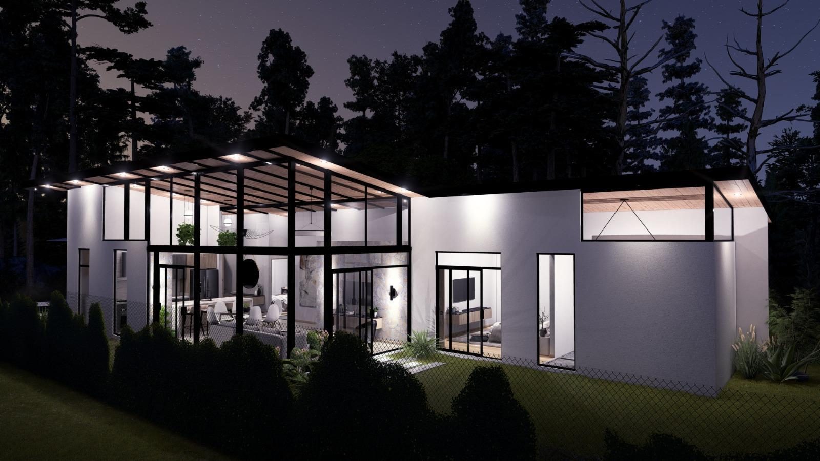 Fachada posterior de Residencia Aura iluminada de noche, con el área social completamente acristalada