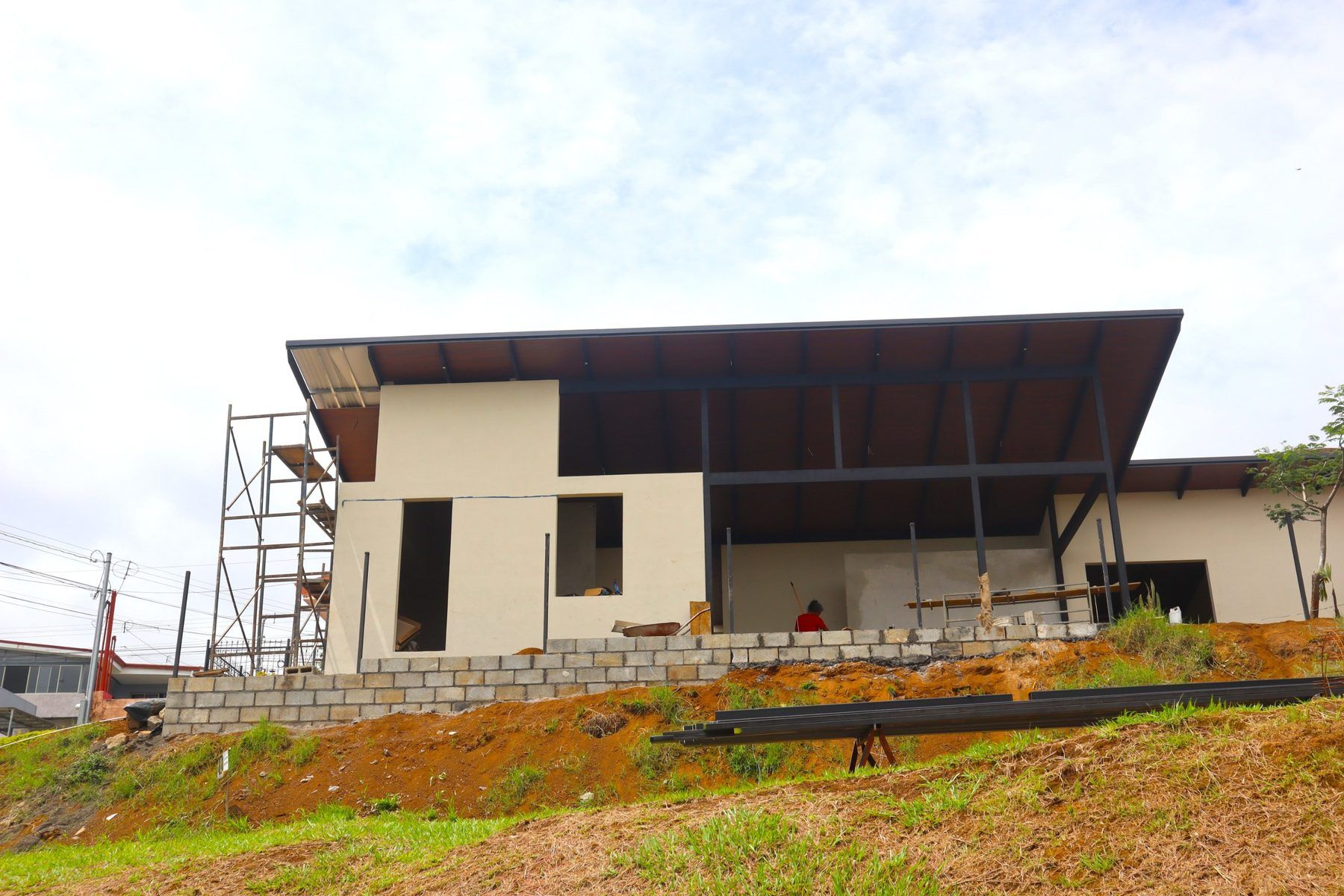Residencia Aura en construcción vista desde el lote posterior, con el techo y la estructura metálica terminados